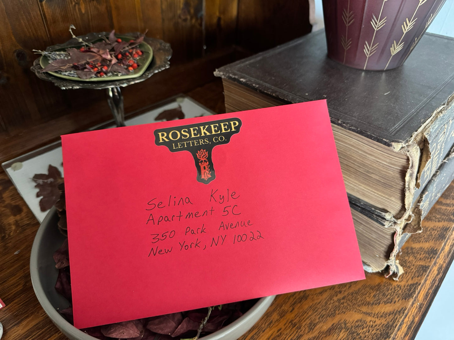 Red envelope with 'Rosekeep Letters Co.' branding on a wooden surface.