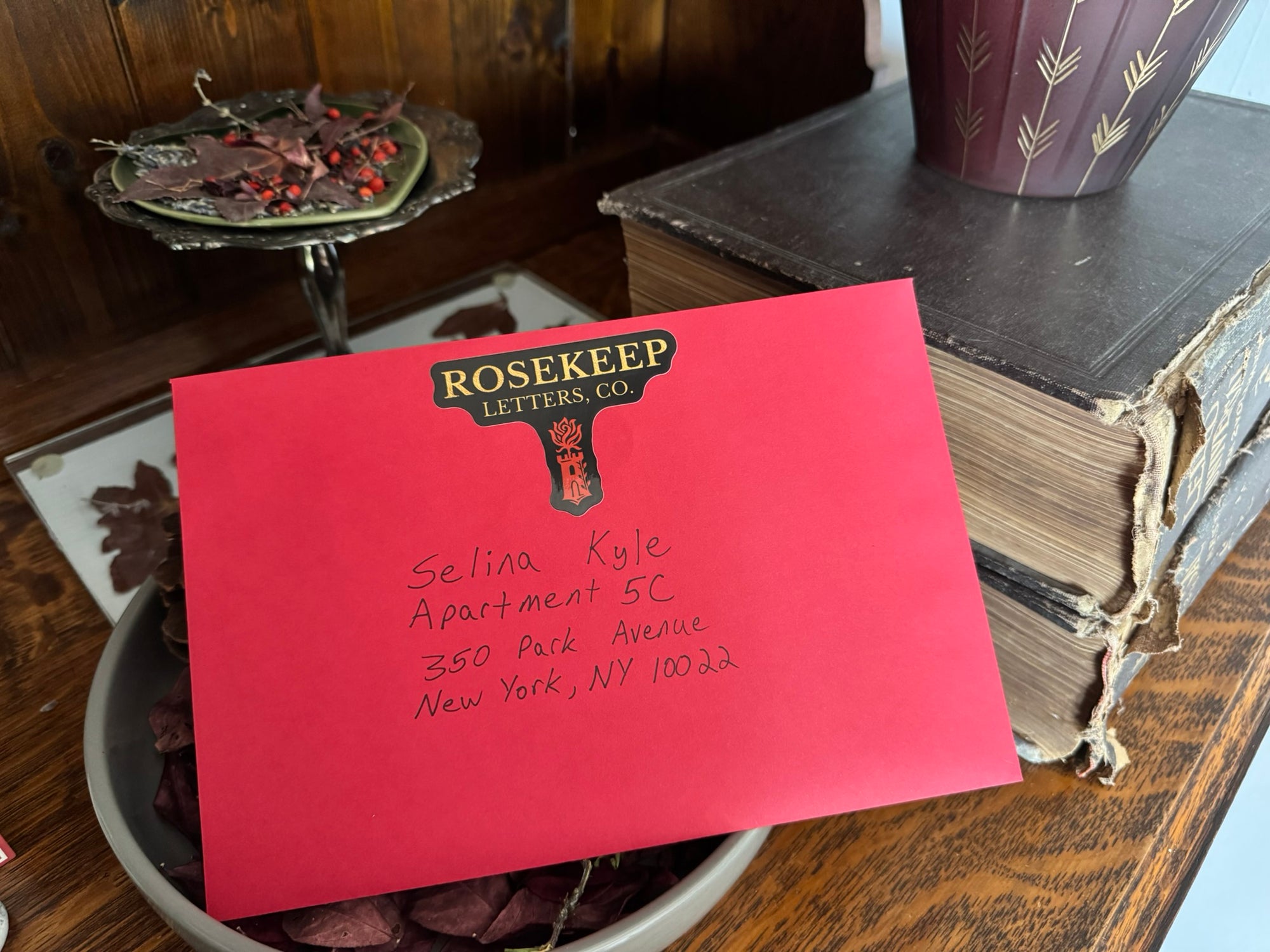 Red envelope with 'Rosekeep Letters Co.' branding on a wooden surface.