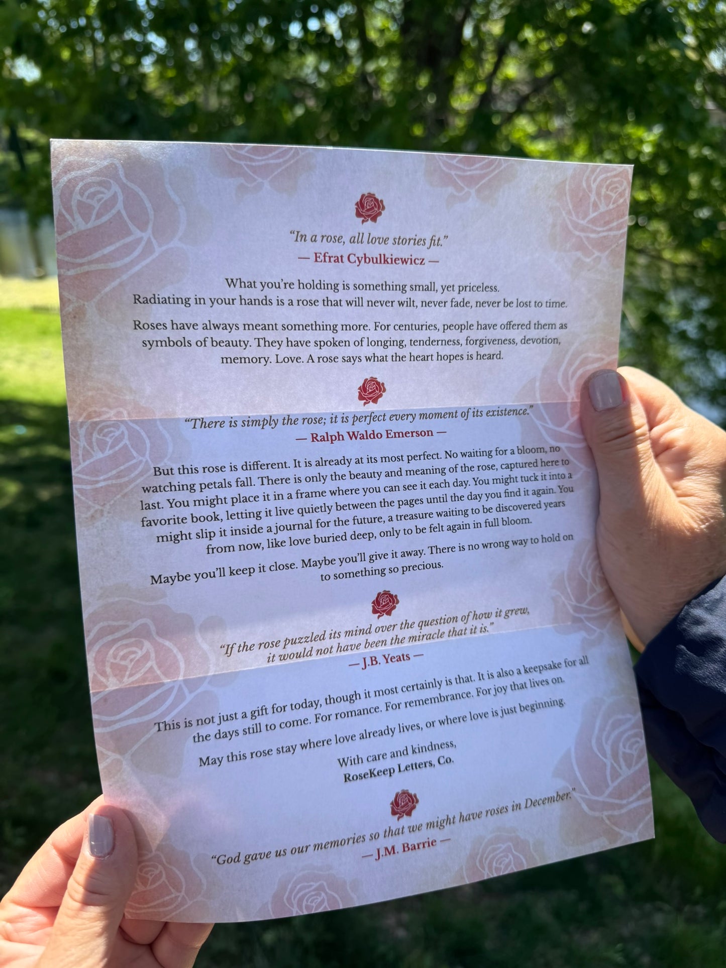 Hand holding RoseKeep Romantic Letter with text and decorative elements against a natural background